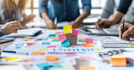 Travel managers writing travel management software ideas on sticky notes in an office room
